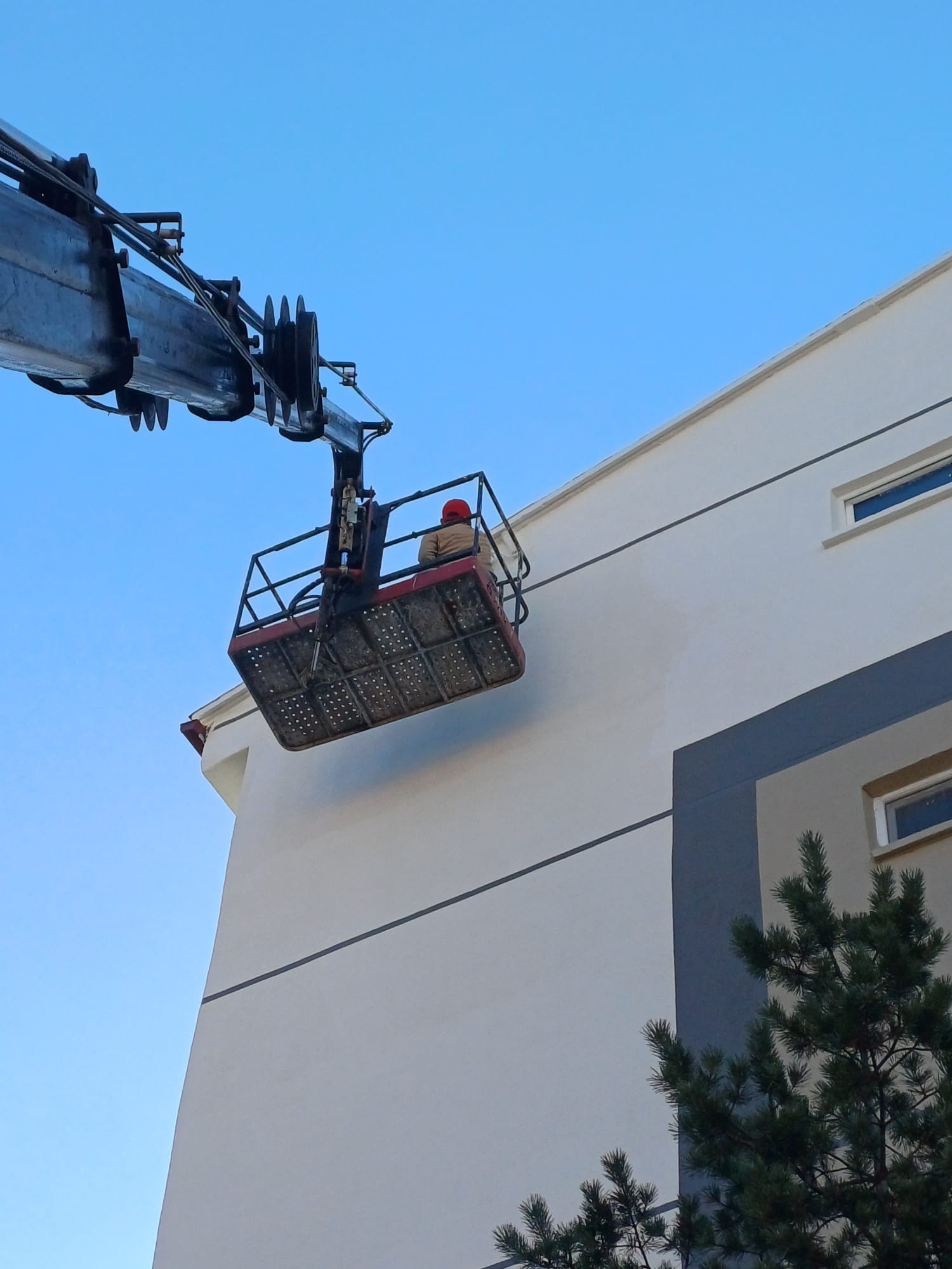 Yüksek cephede sepetli vinç ile dış cephe boya yapan operatör
