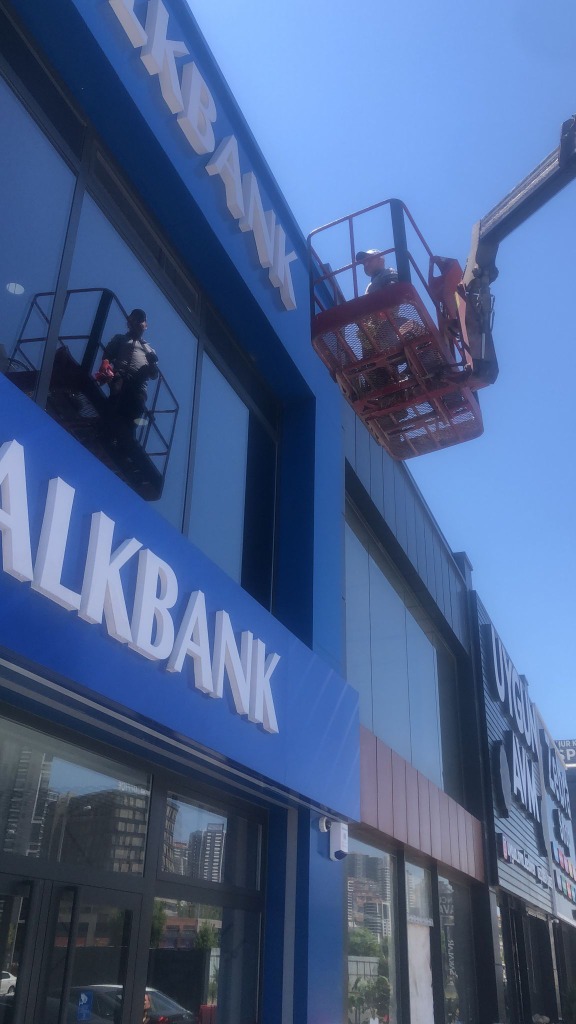 Keçiören Ovacık Halkbank Şubesi mavi cephesinde uzman sepet içinde çalışırken — dış cephe cam temizliği son aşama